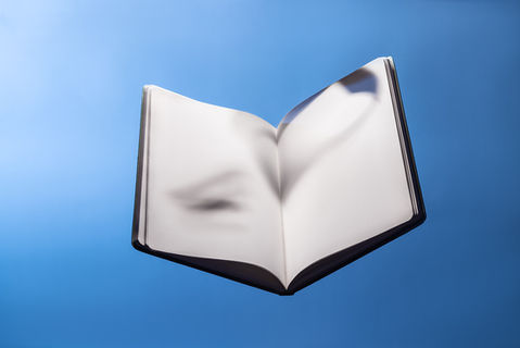 Fine art modern surrealist photography. A book floating in blue infinite space. Open notebook, white pages with shadows on them.