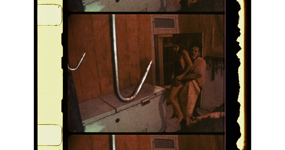 Film strip showing a large hook in a dimly lit room. Two people are in the background, one carrying the other. Predominantly brown tones.