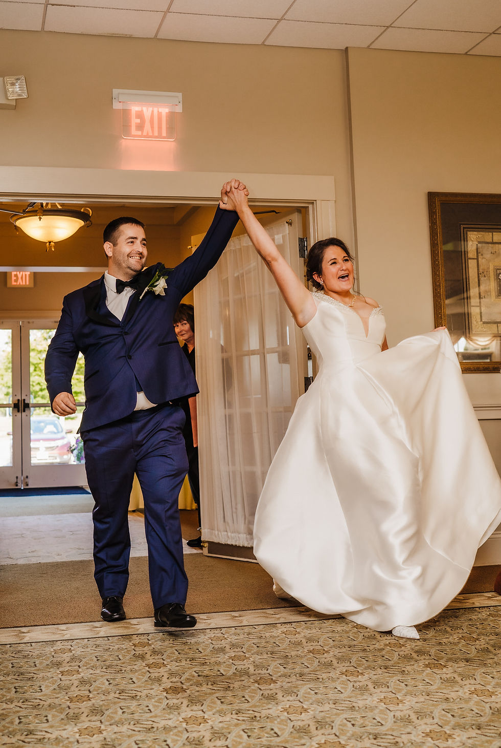 The newlyweds are making an entrance to their wedding reception while holding hands up in the air.