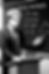 Monochrome manga illustration of a tutor at a lectern pointing to IGCSE Physics formulas on a chalkboard
