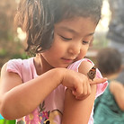 Young girl with a butterfly resting on her shoulder.