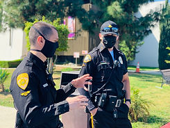 Two male motor escort officers in black uniform having a conversation.
