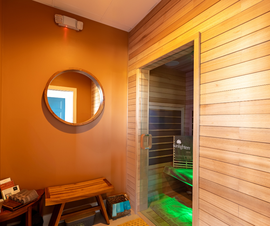 Cedar infrared sauna suite with warm amber lighting and a round mirror
