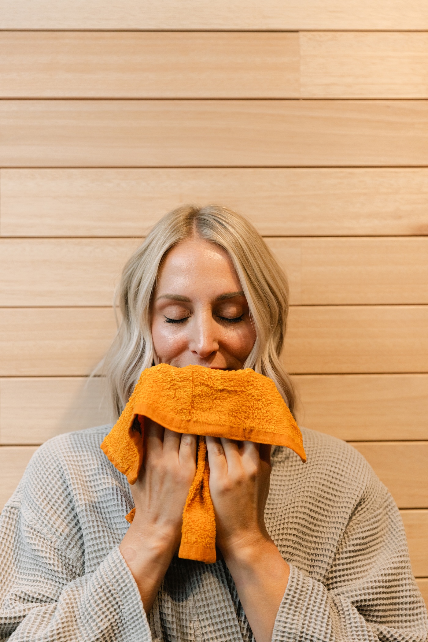 Guest in a robe breathing in a warm peppermint towel after a session