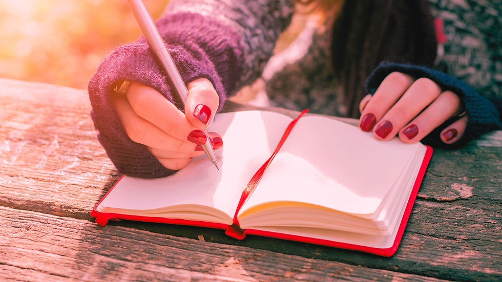 Een vrouw met rode nagellak die in een rood notitieboek schrijft