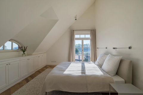 white an natural coloured, sun filled bedroom under slanted roof with two windows