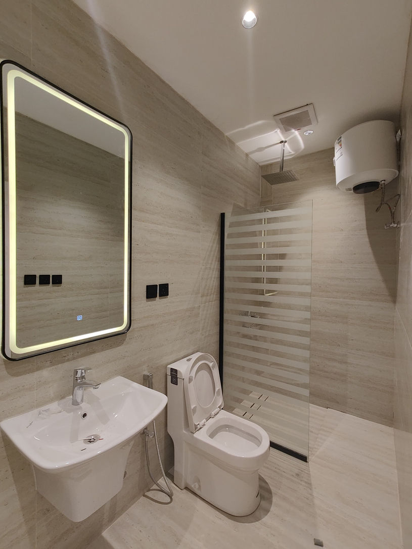 Unfurnished studio bathroom with glass shower screen and illuminated mirror