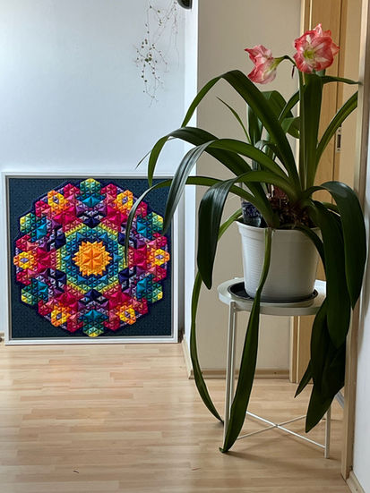 a potted plant sits next to a framed quilt