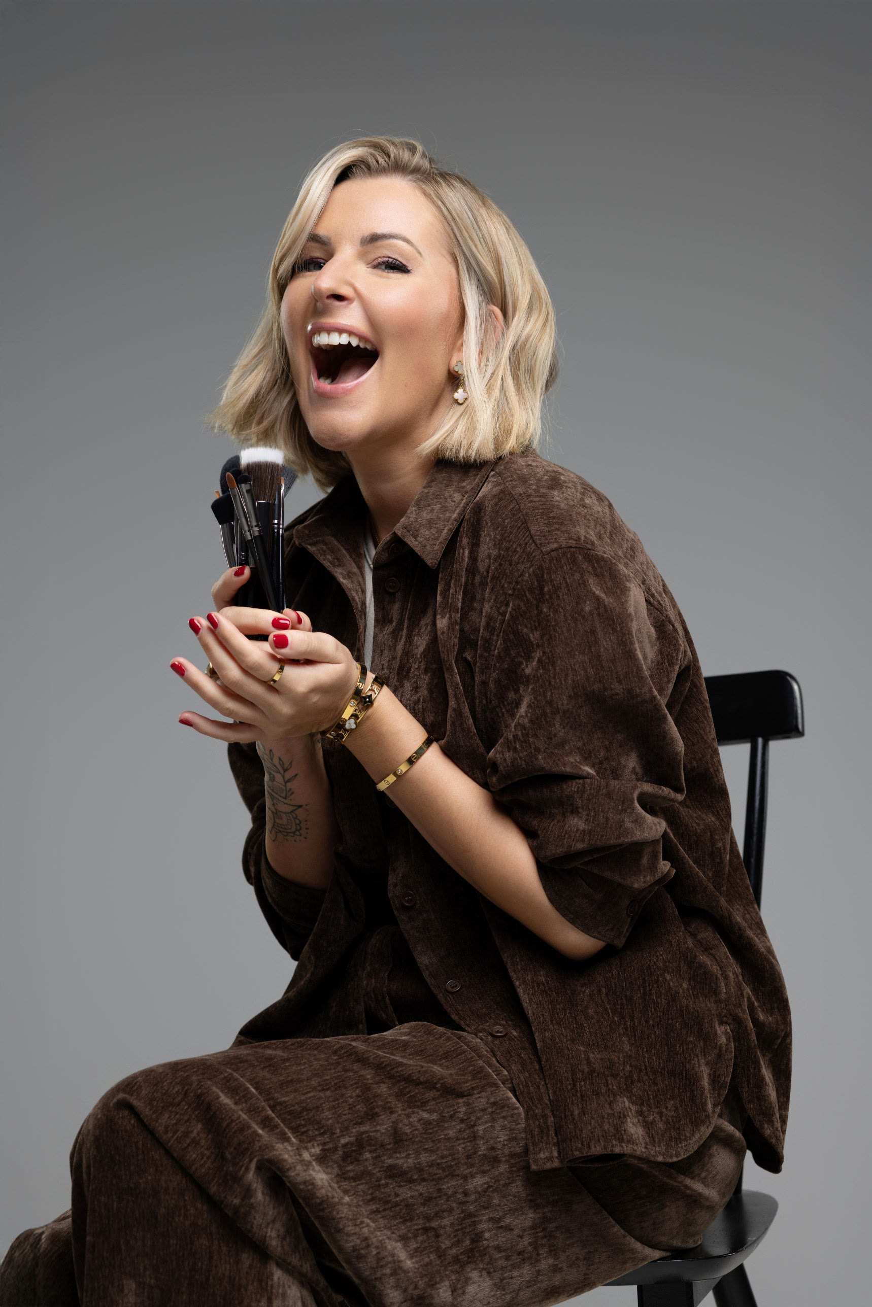 Leonie Aschenbach, Gründerin der Leo Artist Academy, lachend mit Make-up Pinseln in der Hand
