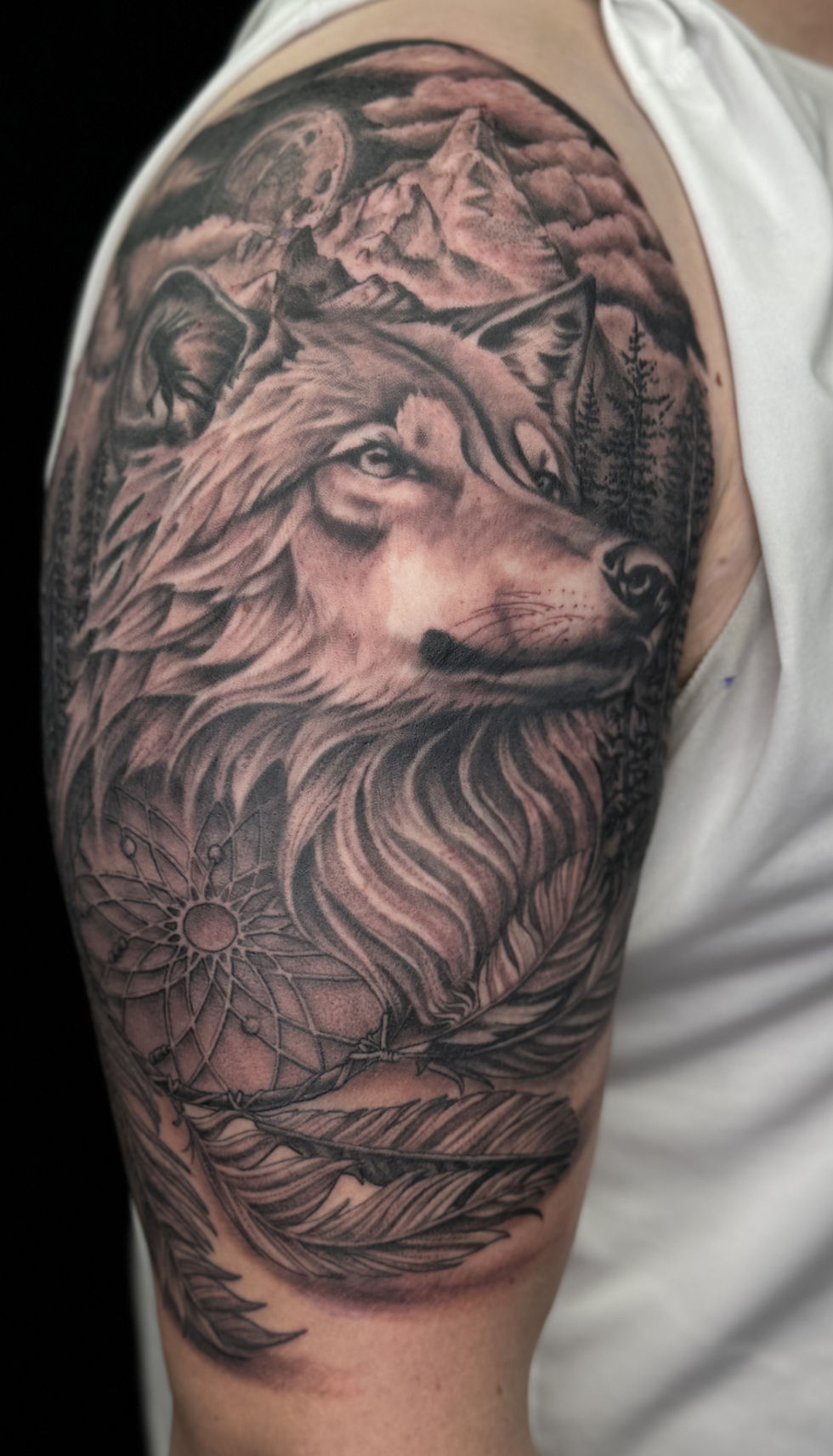 Close-up view of a black and grey realistic tattoo of a wolf on a forearm