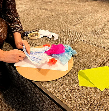 participante em atividade de arteterapia no Singula, papeis rosam amarelo, azul e branco, Joinville, SC, 2025