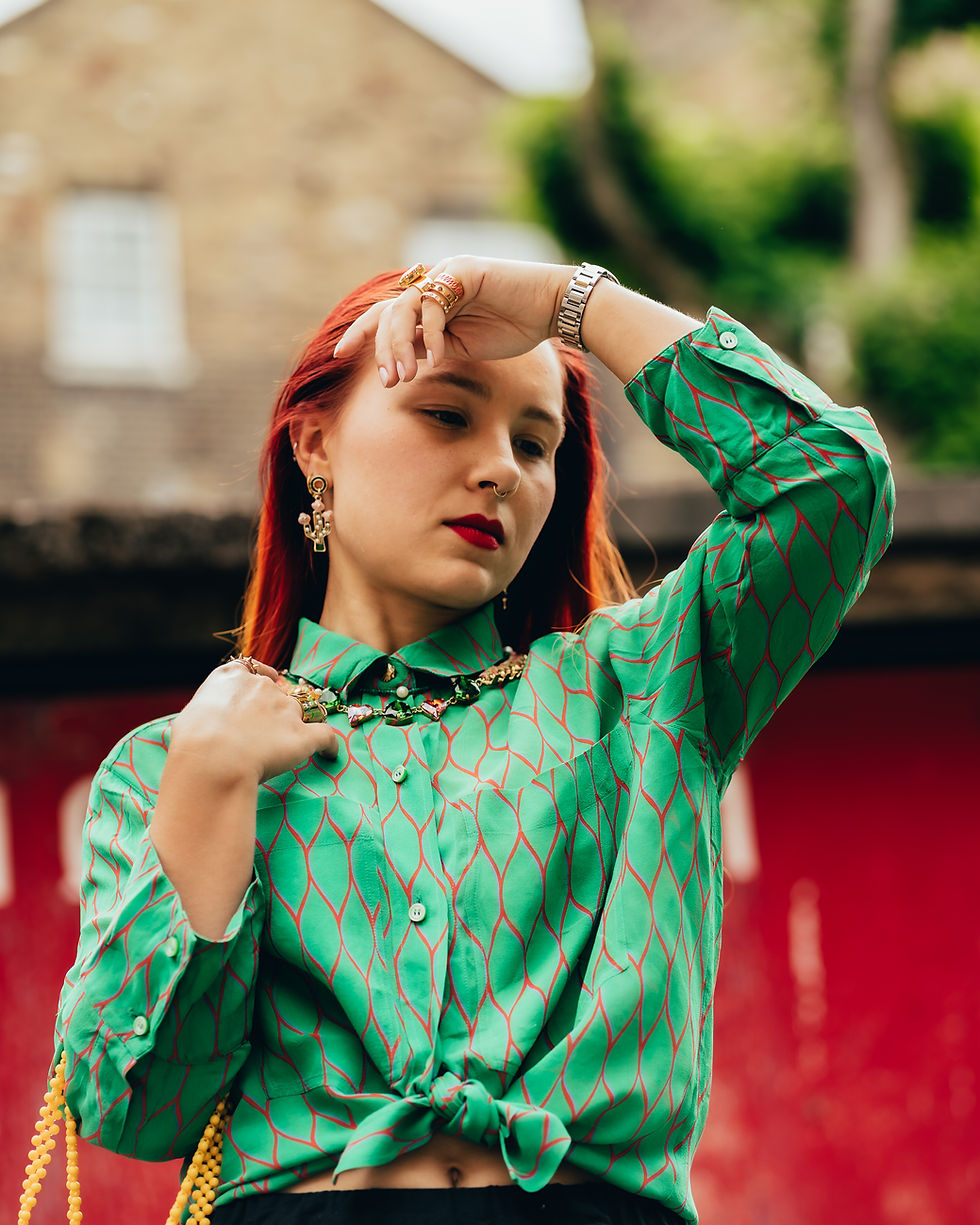 Red head woman in a green shirt holding her hand to her forehead looking down.