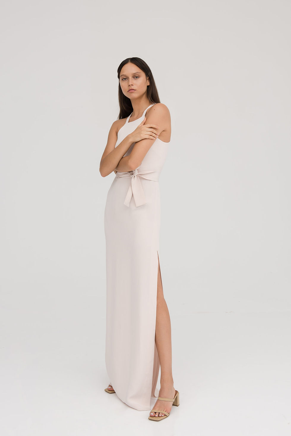 Female model in a white strap full length dress looking at the camera