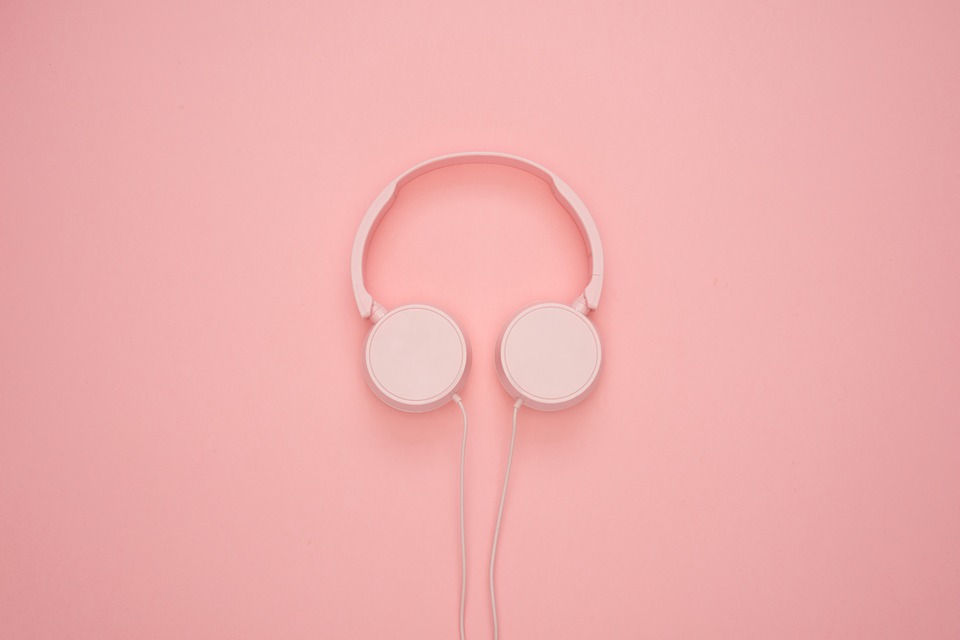 Pastel pink headphones against a slightly darker pink background