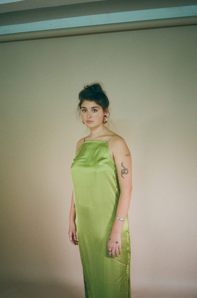 A model in a green silk slip dress with a messy bun