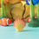 Thumbnail: Wooden Orange Seashell by Bumbu Toys in an ocean-themed small world setup with colourful clownfish in the background