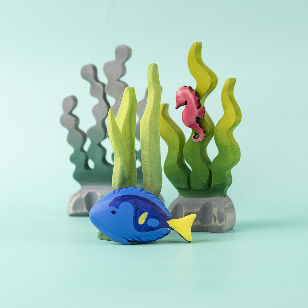 The Bumbu Toys Royal Blue Fish placed among green seaweed and a pink seahorse in a playful underwater small world setup