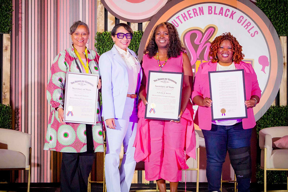 Four women smiling, holding certificates in front of a "Southern Black Girls" sign. Background features pink and green decor.