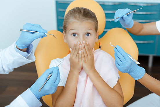 Children emotions and fear of dentist. Scared girl with wide open eyes covers mouth with h