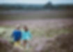 Two children in colourful clothes walking across heathland holding hands
