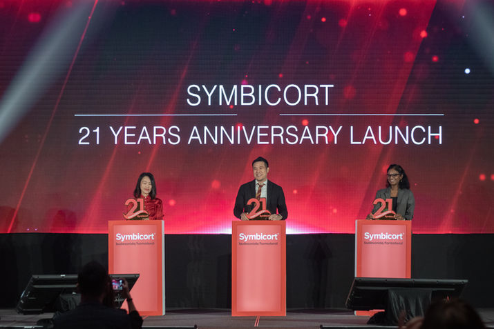 Three professionals commemorating a pharmaceutical company's 21 year anniversary launch