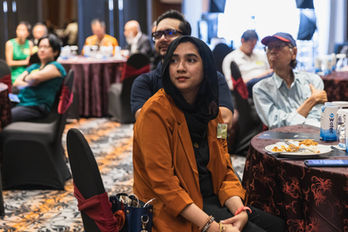 Woman listening attentively to speech given on stage during a law alumni gathering event