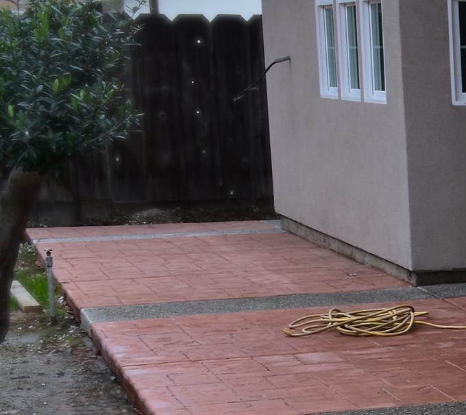 Hormigón teñido de rojo con patrón estampado estilo baldosa y detalles de tiras de grava.
