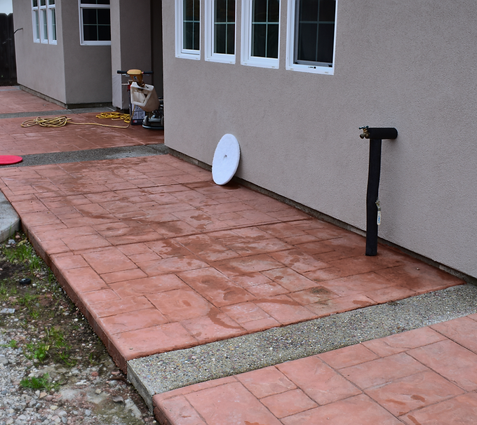 Red stained concrete with tile-style stamped pattern and gravel strip accents.