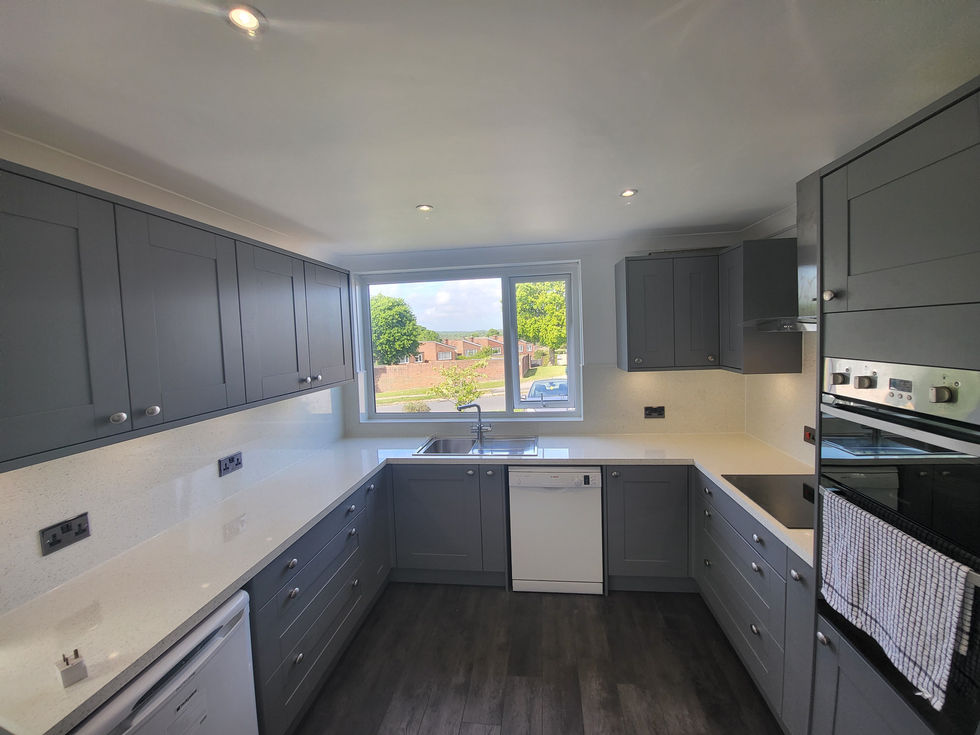 a kitchen with gray cabinets and white counter tops