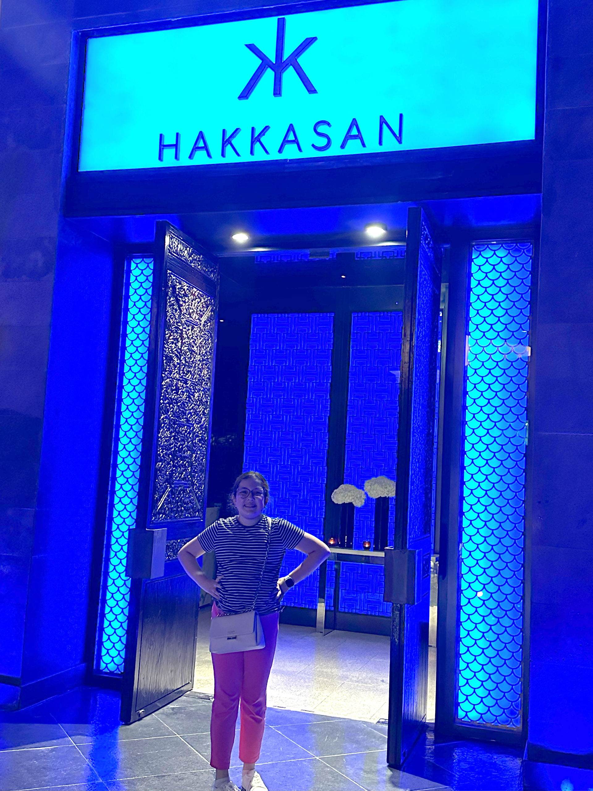 Lit up blue entrance to Hakkasan Restaurant in Dubai with girl standing in entryway
