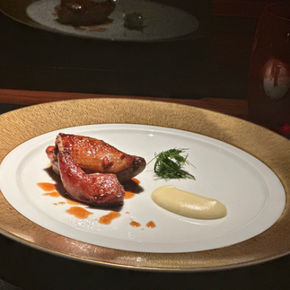 Le Lapin on gold and white decorative plate. Chicken with sauce on top and on the side with garnish