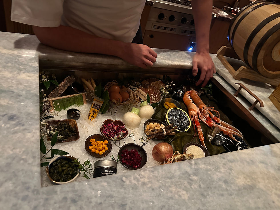 Chef arranges seafood, spices, and vegetables on a countertop display. Includes lobster, eggs, and bowls of colorful ingredients.