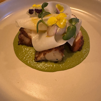 Grilled Octopus with green sauce and white and yellow flowers. Jabri Fine Dining photograph in Miami.