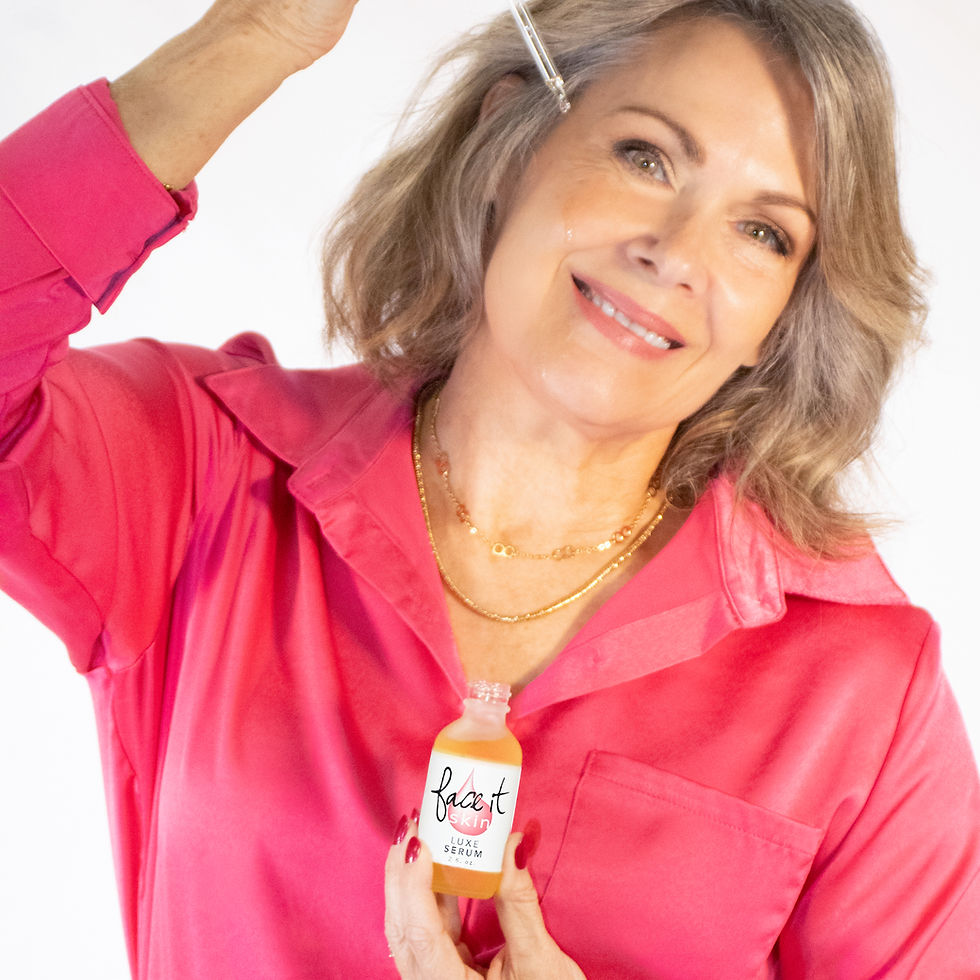 Smiling woman in a bright pink shirt applies face serum with a dropper and holds a Face it Skin Luxe Serum bottle on a white background.