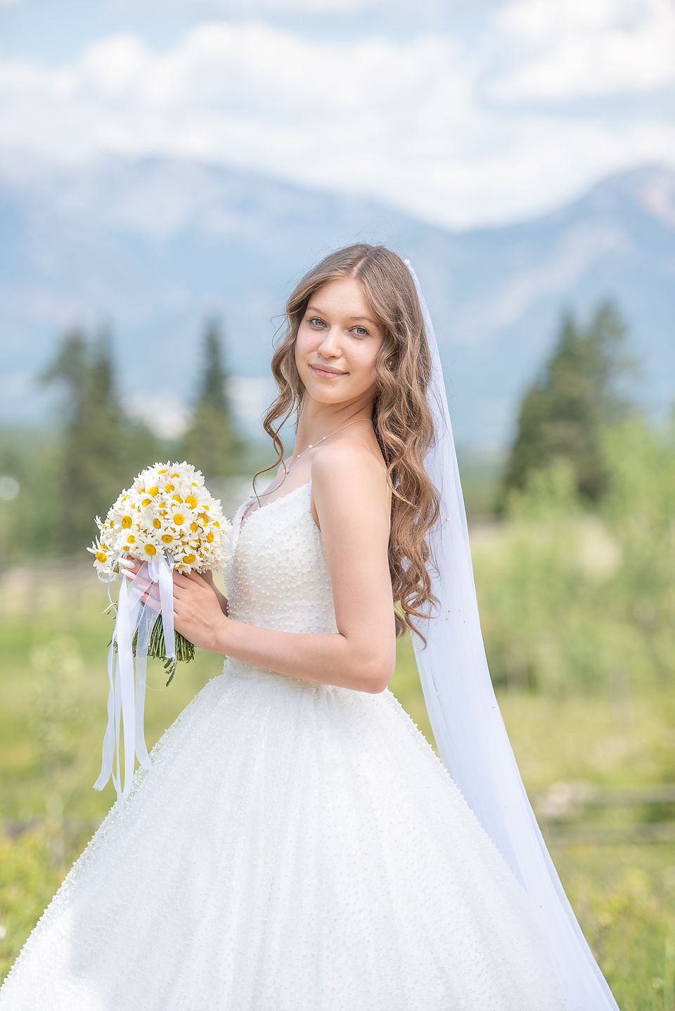Close up of beautiful bride holding a flower bouquet and smiling at the camera. Invermere photographer
