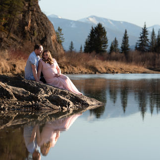 Couple sitting at river enjoying a golden hour sunset