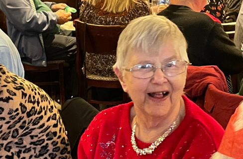 An elderly lady in a Red Christmas jumper captured laughing.