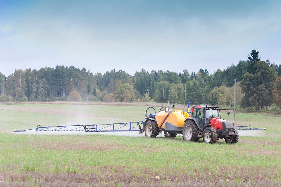 Tractor towing a boom sprayer across a pasture, showing conventional ground-based spraying