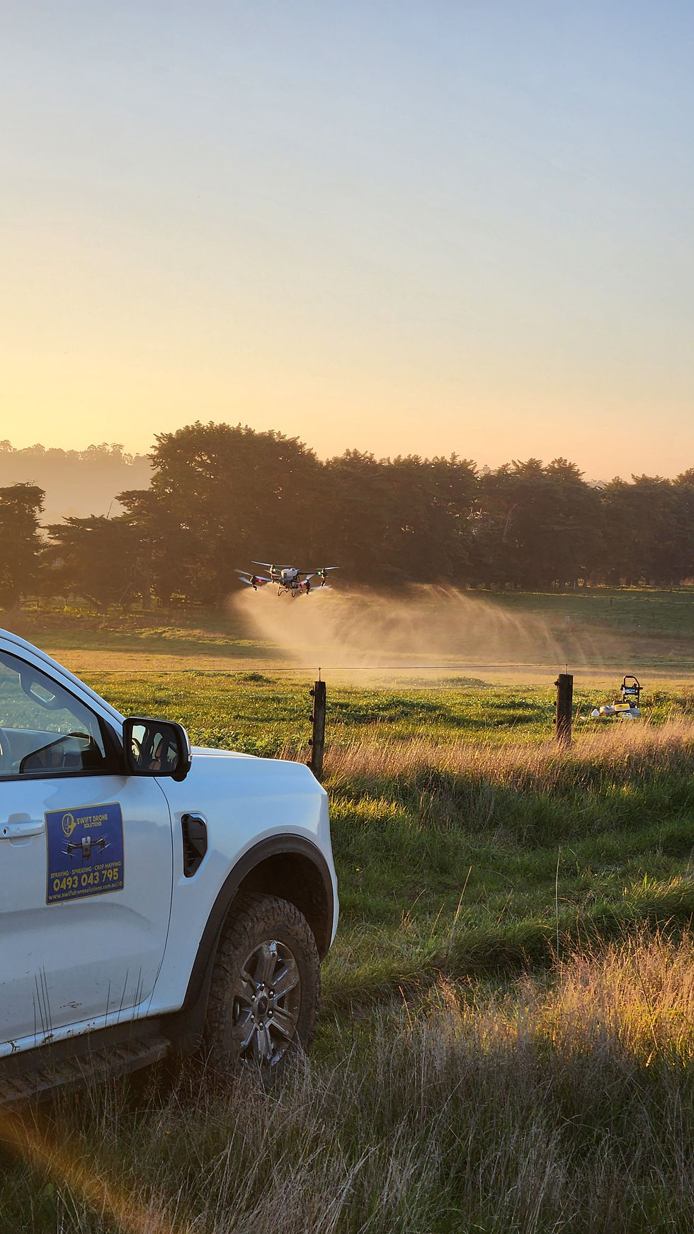 Agricultural drone spraying weeds over a wet Gippsland pasture beside a Swift Drone Solutions vehicle