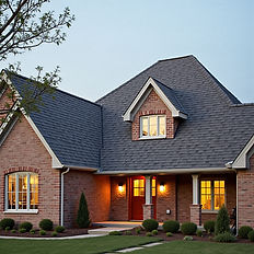 Front view of a brick house with dormer windows and lit entrance at dusk