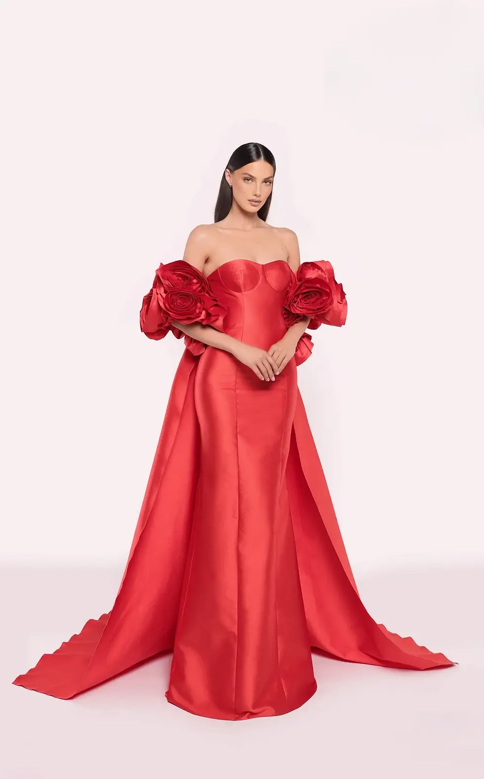 Red corset ball gown with oversized rose-shaped sleeves and a sweeping train.