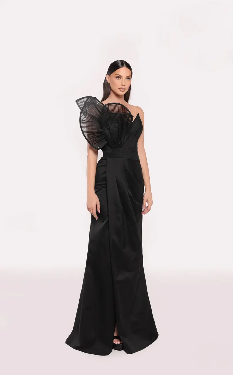 A model in a black one-shoulder evening dress with an oversized pleated design on the shoulder and a sleek, structured silhou