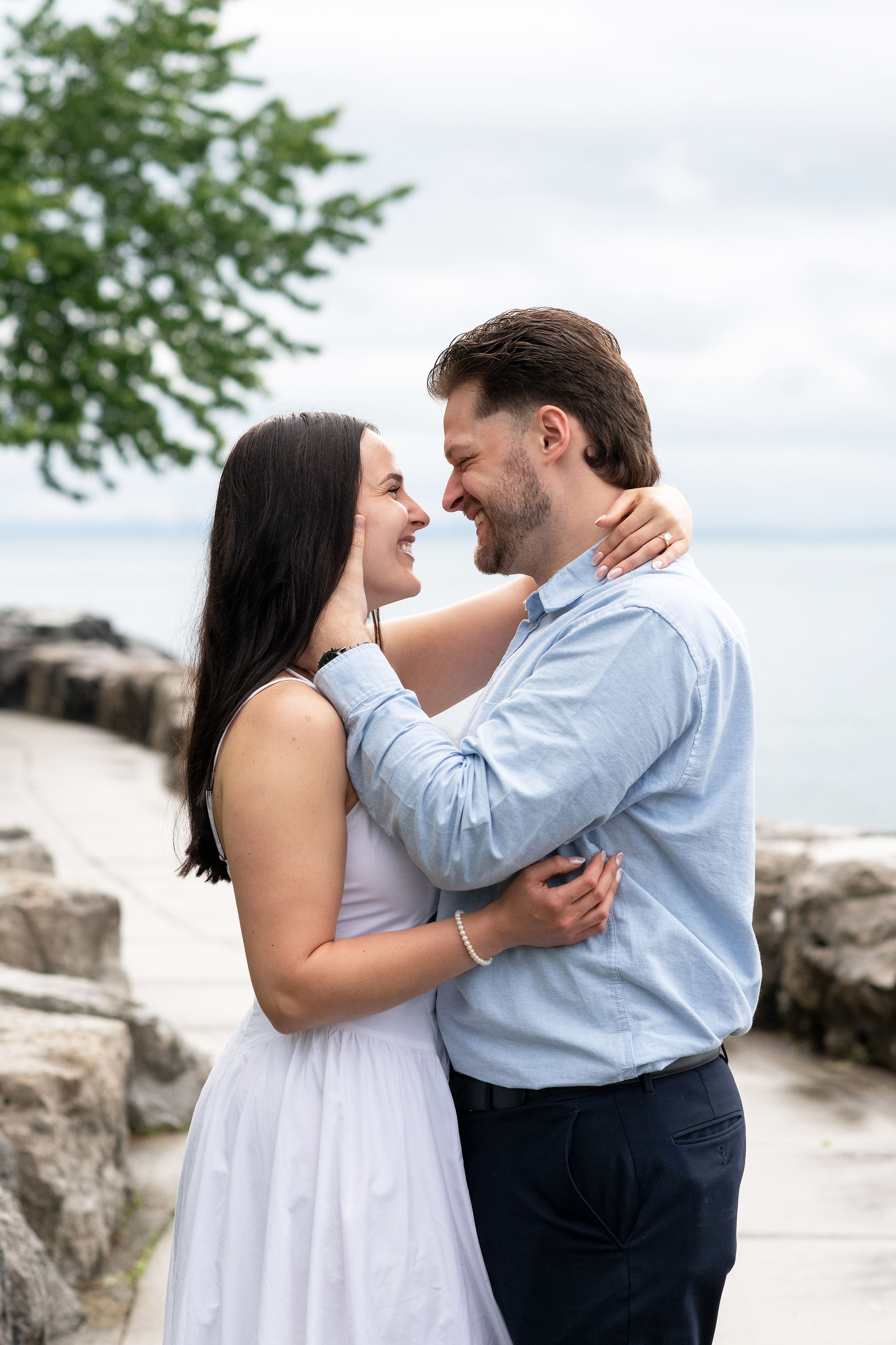 Candid engagement photo of newly engaged couple laughing by the waterfront.