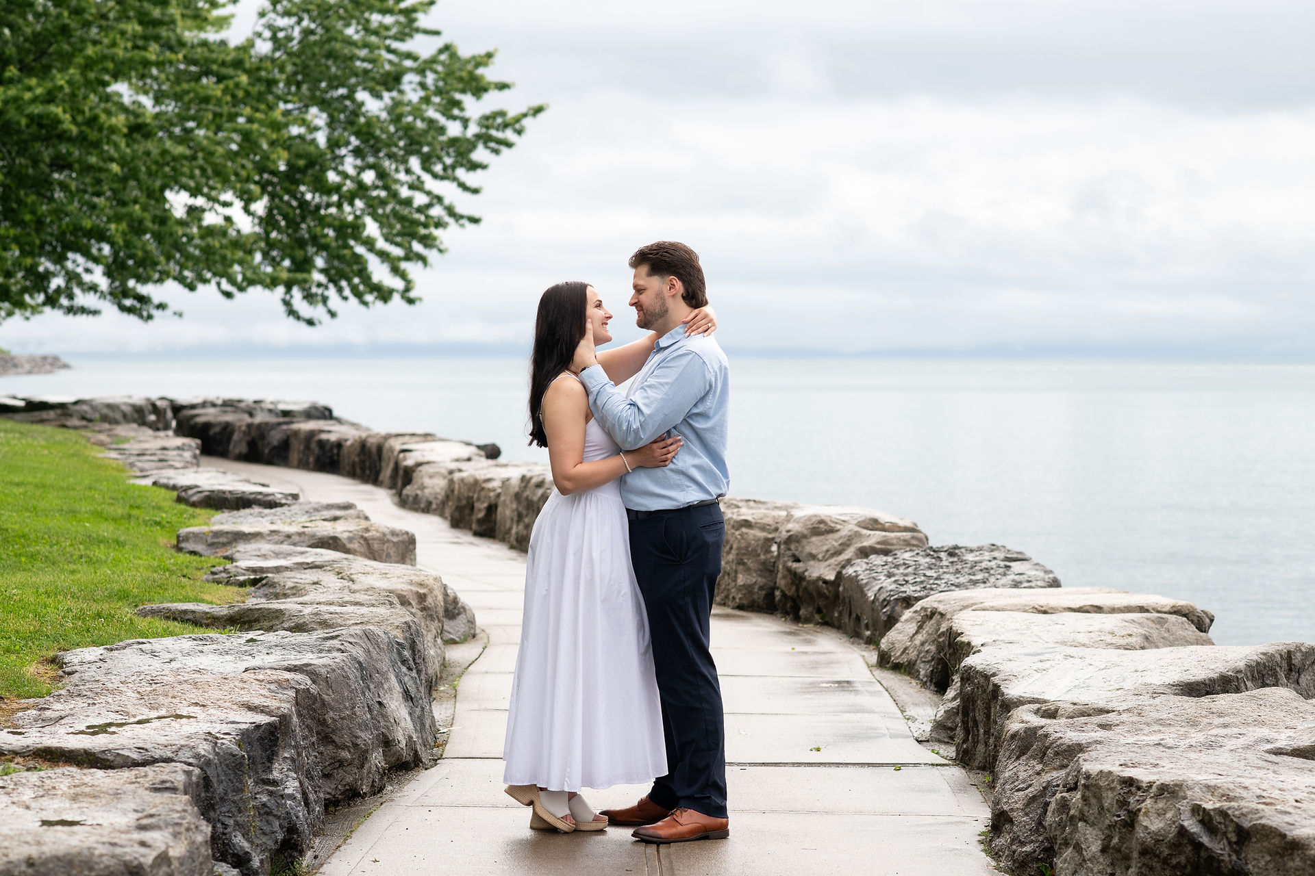 Candid engagement photo of newly engaged couple laughing by the waterfront.