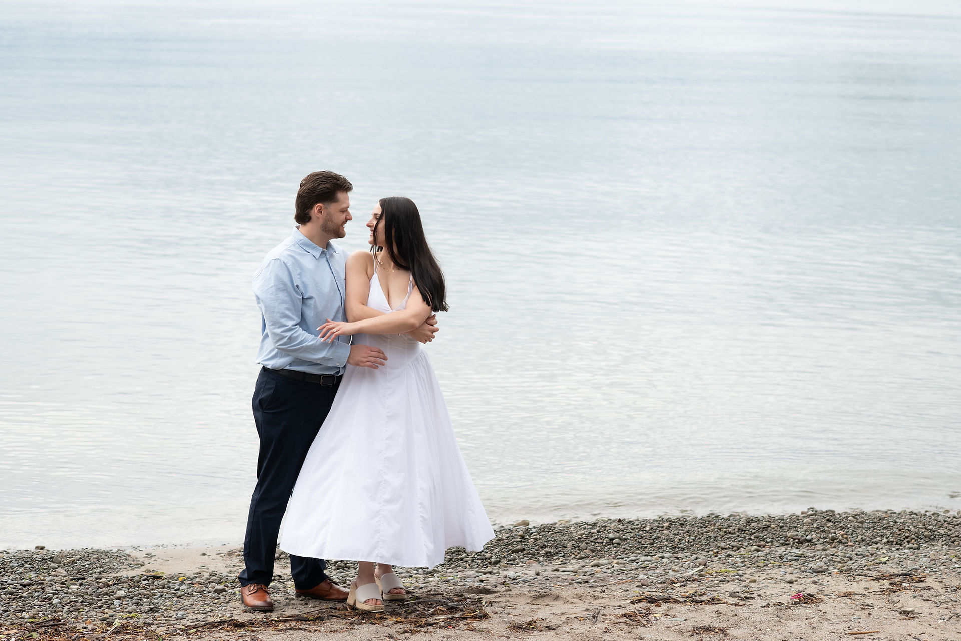 Candid engagement photo of newly engaged couple laughing by the waterfront.