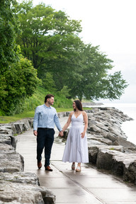 Engagement photos of a happy couple by the lake on a rainy afternoon.