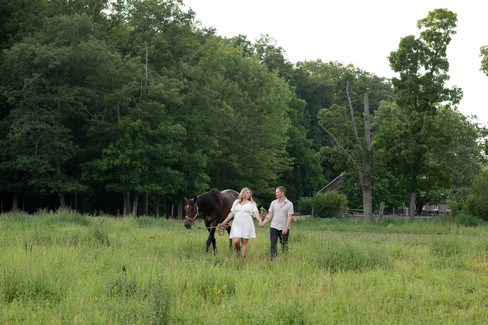 Future bride and groom enjoying a quiet moment with their horses outdoors.