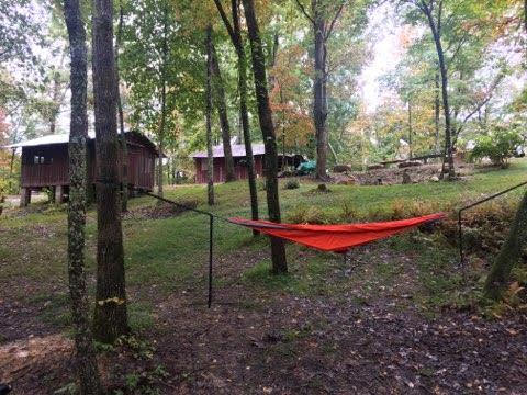 a hammock attached to two trees with cabins in the background