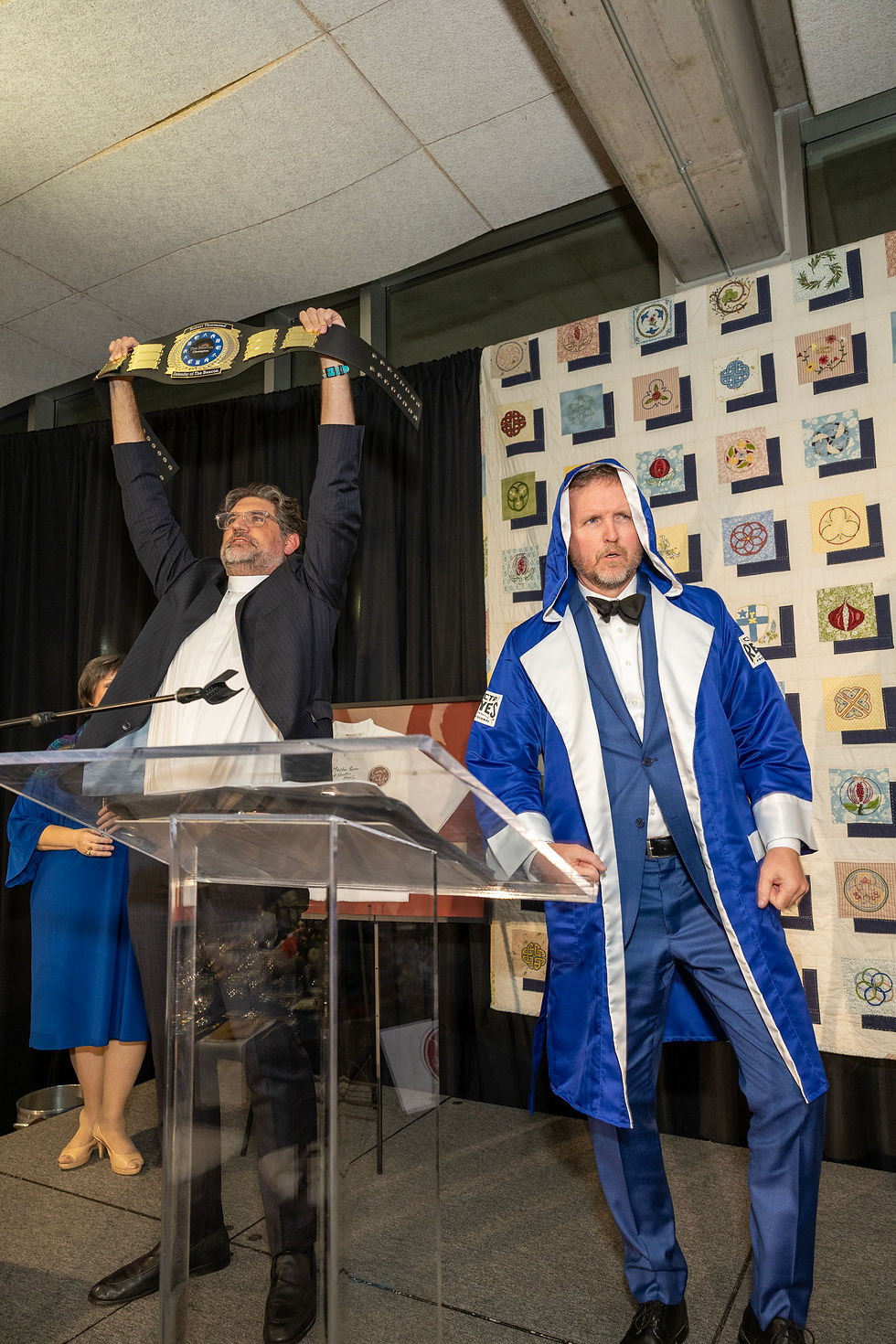Dean Nathaniel Katz hoists Bob's Belt into the air and Bradley Dennison wears the championship robe to the stage to introduce the auction item.