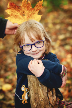 little girl wearing glasses with an autumnal leaf during a family photo session